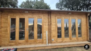 Facciata principale di casa in legno completata, con ampie vetrate e finitura esterna color miele, Scansano, Toscana.