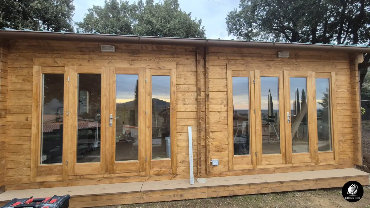 Facciata principale di casa in legno completata, con ampie vetrate e finitura esterna color miele, Scansano, Toscana.