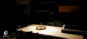 Tavolo da pranzo in legno grezzo in cucina stile industrial chic (scatto in penombra per atmosfera).