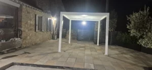 Gazebo o pergola bianca illuminazione notturna su pavimentazione in pietra.